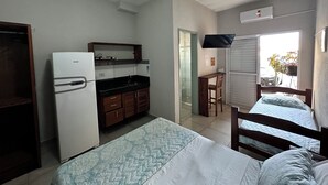 Una habitación pequeña con cama, un escritorio y una kitchenette.