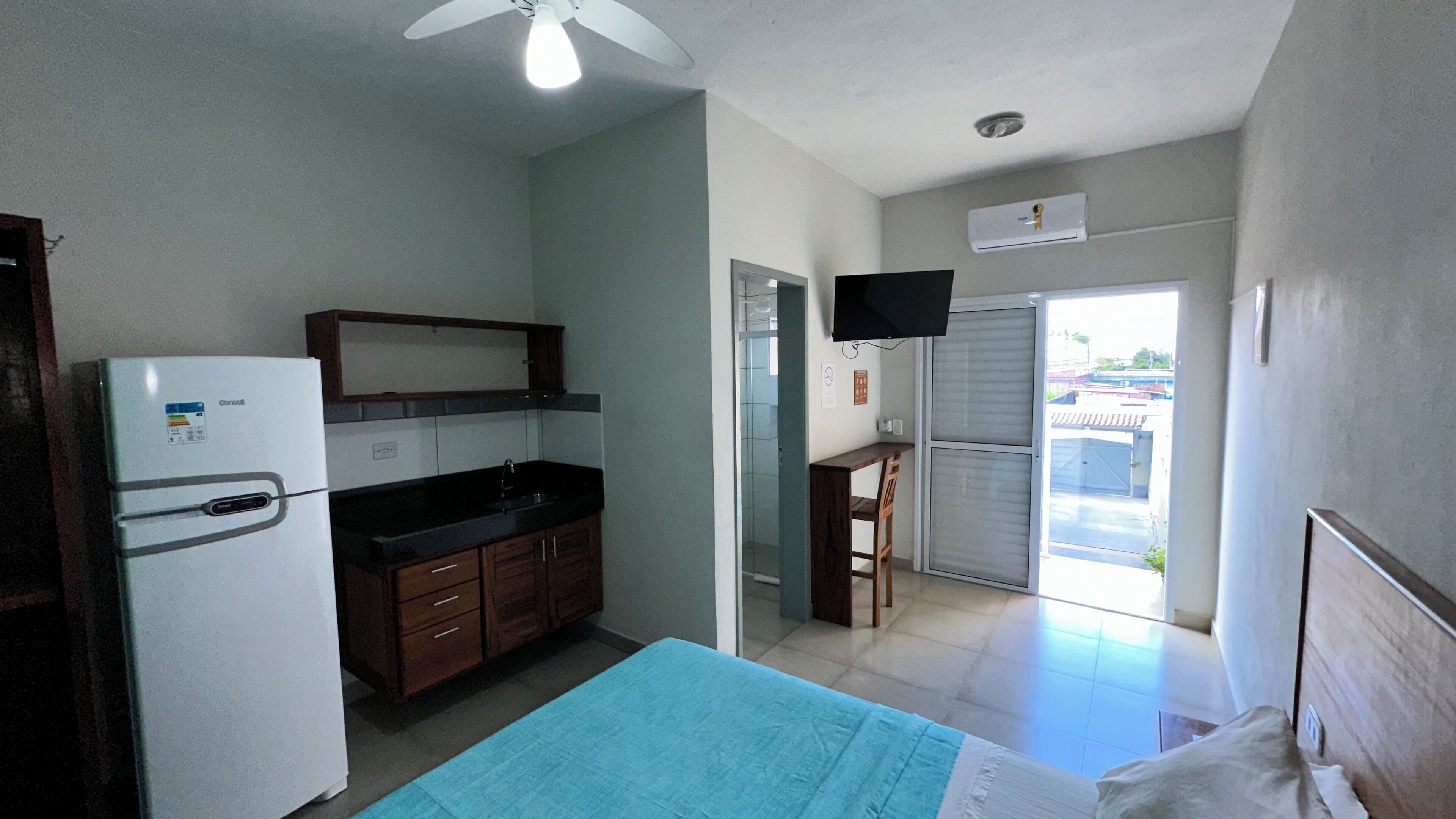 A compact kitchen with a refrigerator, a sink, and a dining area with a table and chairs.