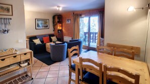 Un salon confortable avec un canapé, une table à manger et des chaises. On y trouve également un meuble en bois et un tableau encadré accroché au mur.