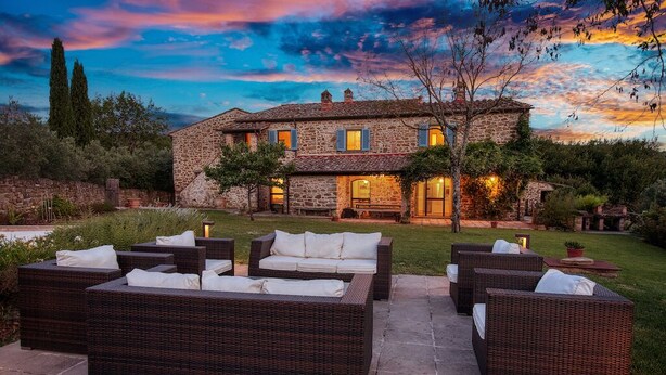 A stone house with a patio area featuring wicker furniture.