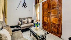 A living room with a sofa, a coffee table, and a wooden door. - Hotel O Desa Wisata Santanamekar (Cisayong)
