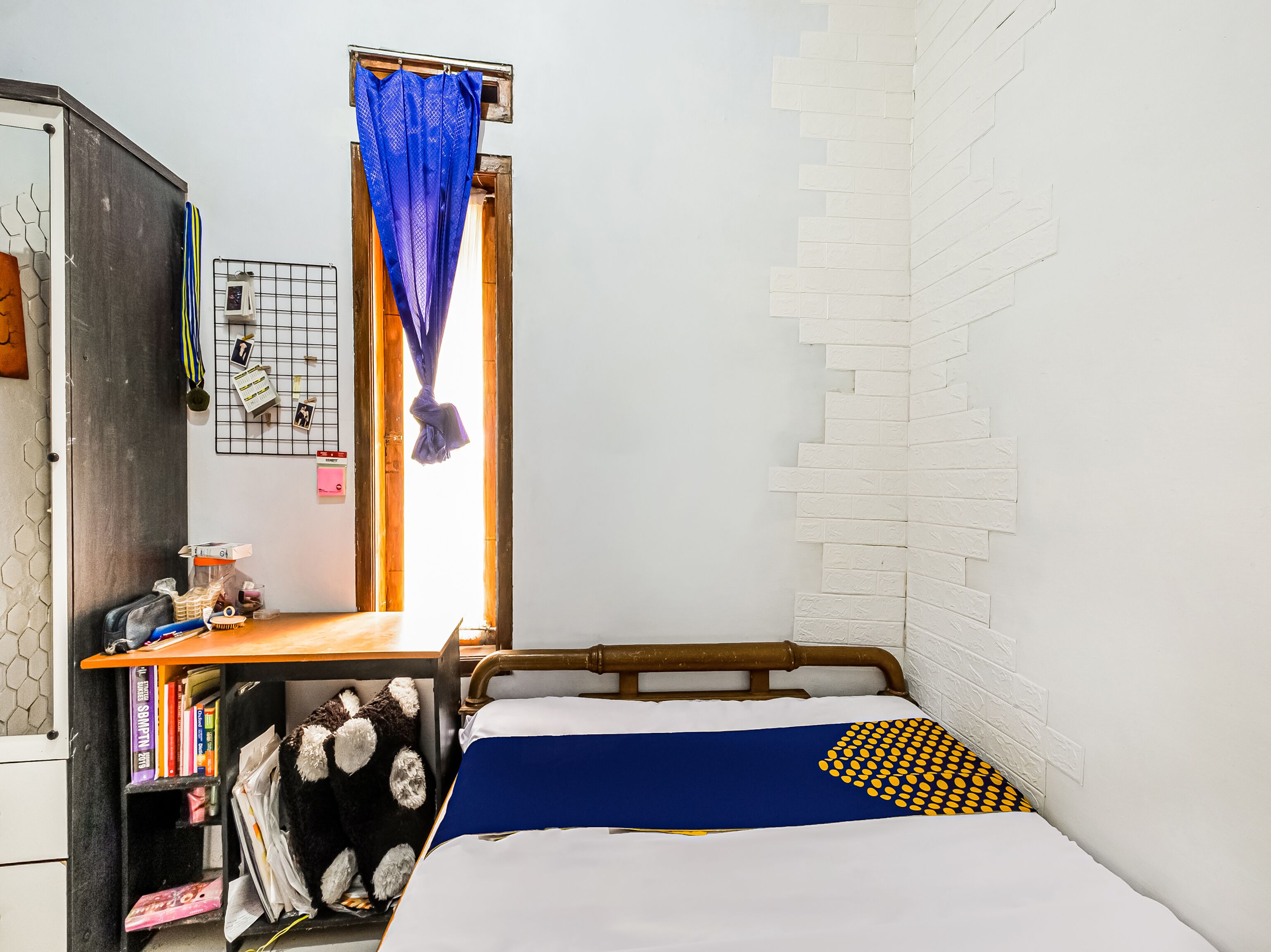 A small, compact room with a bed, a desk, and a wardrobe.