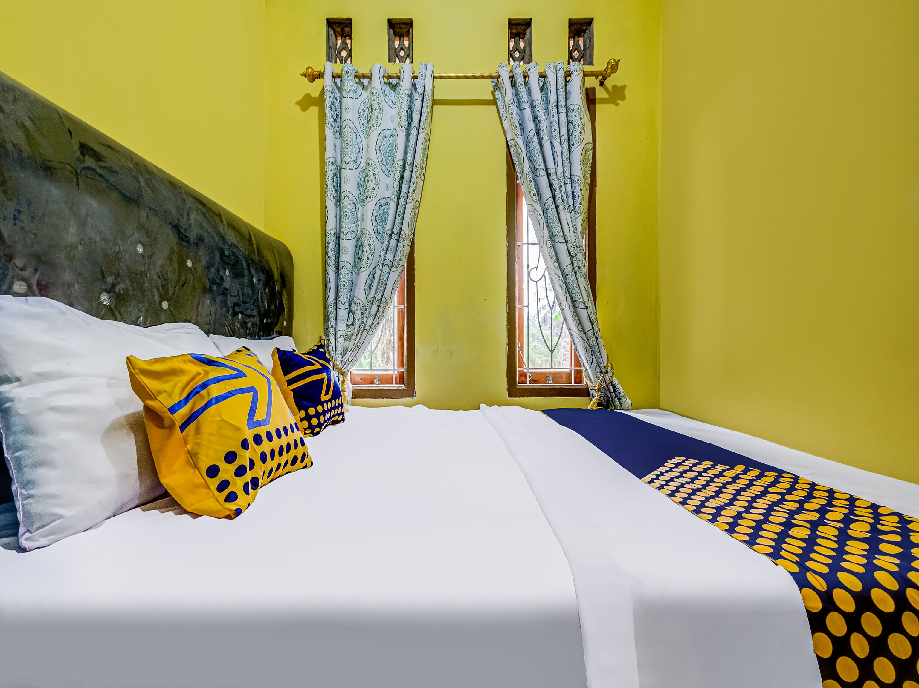 A room with a bed, pillows, curtains, and a window.