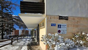 A snow-covered pathway leading to a building with a sign indicating parking for handicapped individuals. - Beautiful 3-room apt, renovated, central, facing slopes, 6 pers., balcony, parking (Pra-Loup)