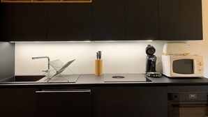 A modern kitchen with dark cabinets, a built-in microwave, a coffee maker, and a knife block. - Beautiful 3-room apt, renovated, central, facing slopes, 6 pers., balcony, parking (Pra-Loup)