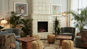 A cozy living room with a fireplace, comfortable seating, and decorative plants. - The Hoxton, Berlin (Berlin)