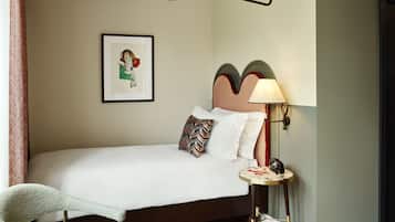 Uma cama bem arrumada com almofadas, um abajur e um quadro na parede.