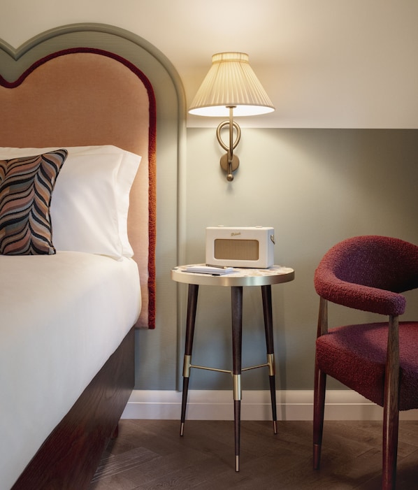 A hotel room with a bed, a table with a radio, a lamp, and a chair. - The Hoxton, Berlin (Berlin)