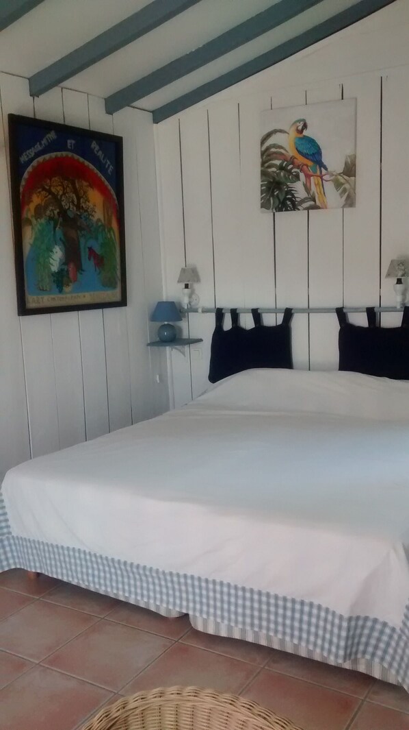 A bedroom with a bed, a wall-mounted painting, a lamp, and a small shelf. - A charming and peaceful cottage—this self-contained lodging is ideal for hikers (OSSES)