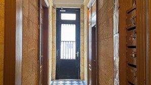 Ein Flur mit Schachbrettboden, einer schwarzen Tür mit Fenster und Holzwänden.