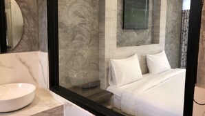 Quarto moderno com uma cama grande, uma pia redonda branca e um quadro na parede.