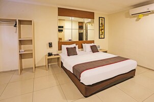 Ein Hotelzimmer mit einem großen Bett, einem Holzkopfteil, einem Nachttisch, einem Kleiderschrank und einem Spiegel.