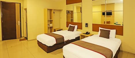 Habitación de hotel con dos camas, un armario, un espejo y un televisor.