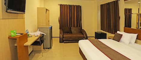 Une chambre d’hôtel avec un lit, un bureau, une chaise, une télévision et un miroir.