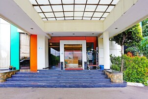 Ein Hotel Eingang mit Glastür, rotem Teppich und einer überdachten Zugangsbegrenzung.
