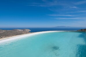 A coastal landscape with a clear blue sky, a sandy beach, and a calm turquoise sea. - 360 Sunset Villa with Private Pool (Mykonos)