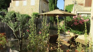 A rustic courtyard with stone buildings, a wooden fence, and a garden with flowering plants. - Charming village house near Bédoin, at the foot of Mont Ventoux (Crillon-le-Brave)