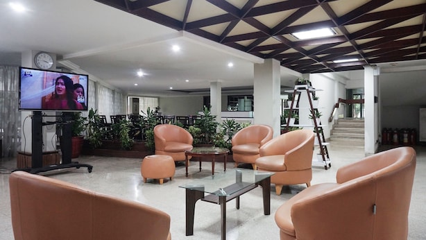 A spacious lobby with modern furniture, a television, and a staircase in the background.