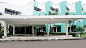 A building with a covered entrance, a signboard, and a trash bin.