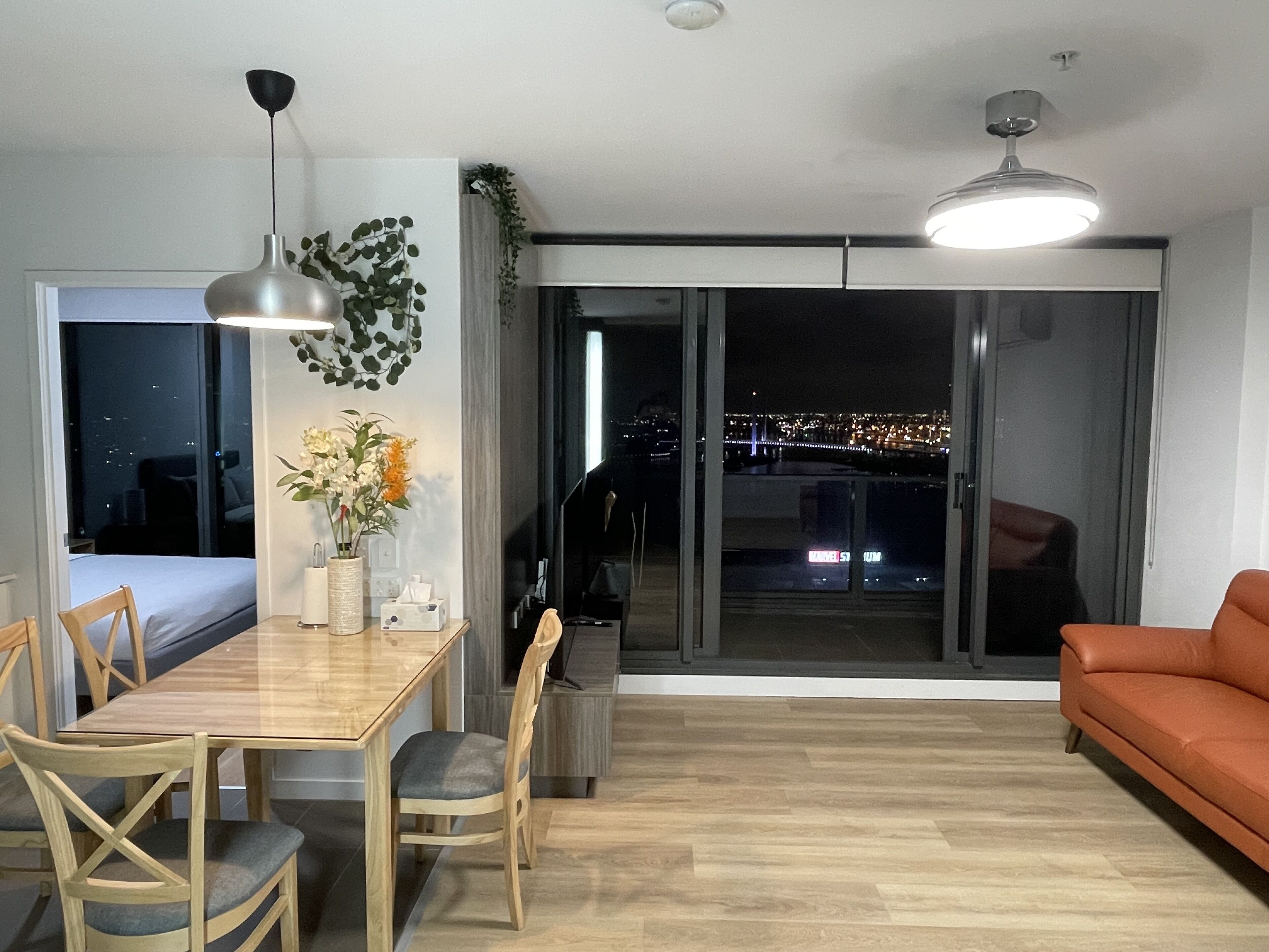 Una sala de estar moderna con una mesa de comedor, sillas, un sofá y un amplio ventanal con vista a la ciudad.