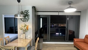 A modern living room with a dining table, chairs, a sofa, and a large window with a city view. - Luxury 2B2B Well Furnished Spectacular View (Melbourne)
