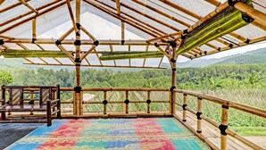 A bamboo structure with a colorful patterned floor, wooden railings, and a view of a lush green landscape. - OYO Homes 90849 Cibeunying Homestay Cibodas Maribaya (Lembang)