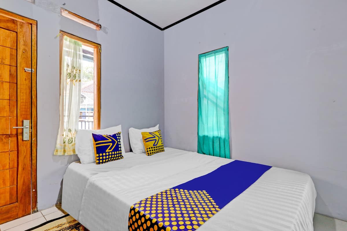 A bedroom with a bed, a wooden door, and a window with curtains.