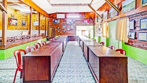 A long dining table with chairs, wooden walls, and framed pictures. - OYO Homes 90849 Cibeunying Homestay Cibodas Maribaya (Lembang)