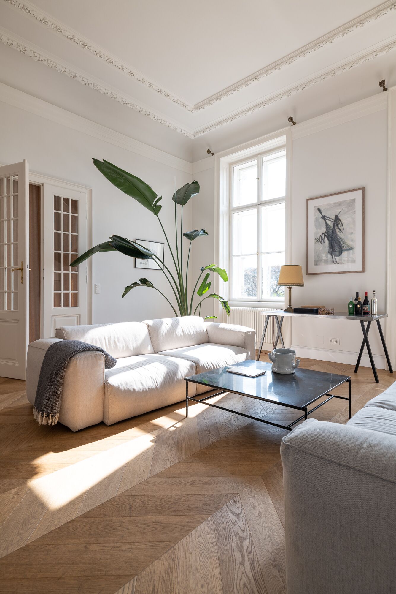 Un salon spacieux avec un canapé blanc, une table basse et de grandes fenêtres qui laissent entrer la lumière naturelle.