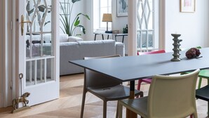 A dining area with a table and chairs, a plant, and a lamp.