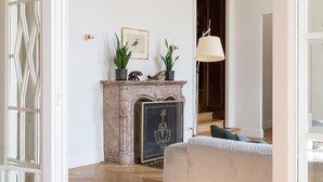 A spacious living room with a fireplace, a sofa, and a lamp.