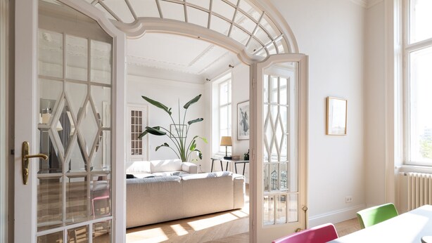 A room with a large arched doorway, a sofa, a table with chairs, and a radiator.