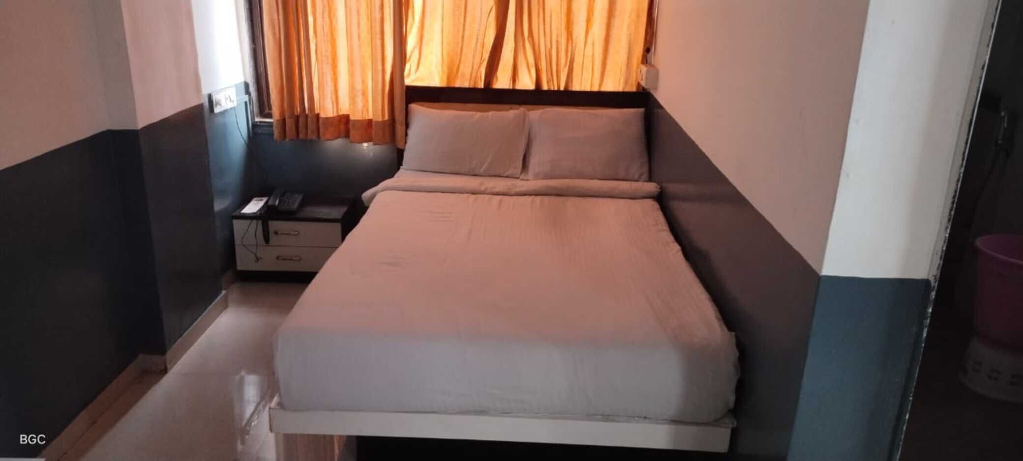 A small, neatly arranged bedroom with a bed, a nightstand, and a dresser.