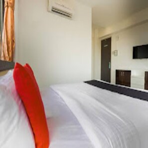 Quarto de hotel com uma cama, uma televisão fixada na parede e uma porta que dá para outro cômodo.