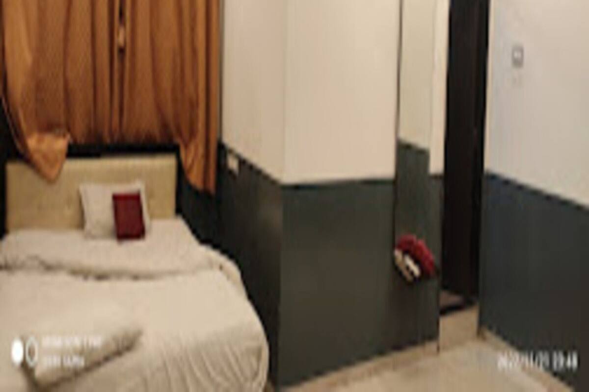 A hotel room with a bed, a bedside table, a mirror, and a door.