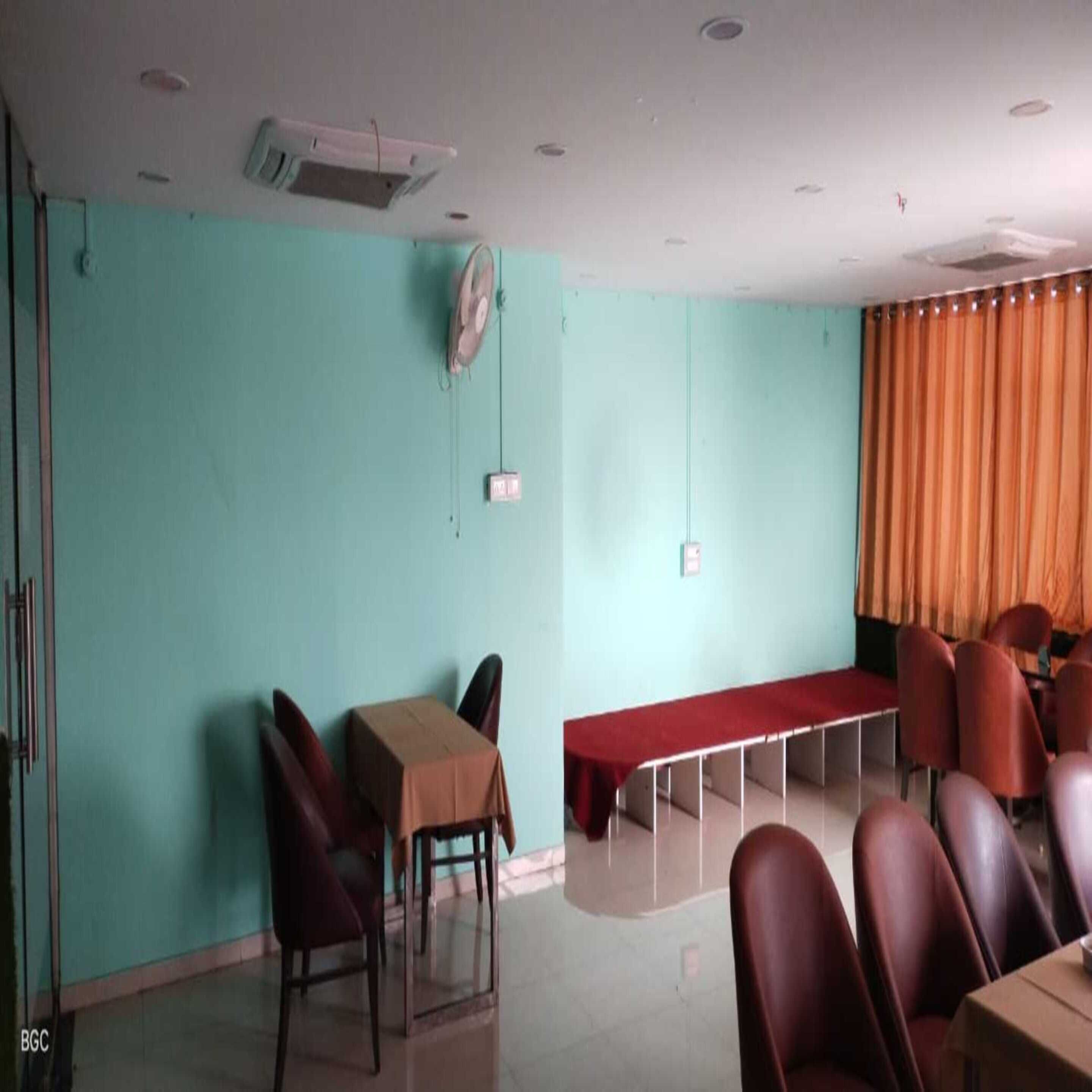 A conference room with teal walls, a table, chairs, and an air conditioning unit.