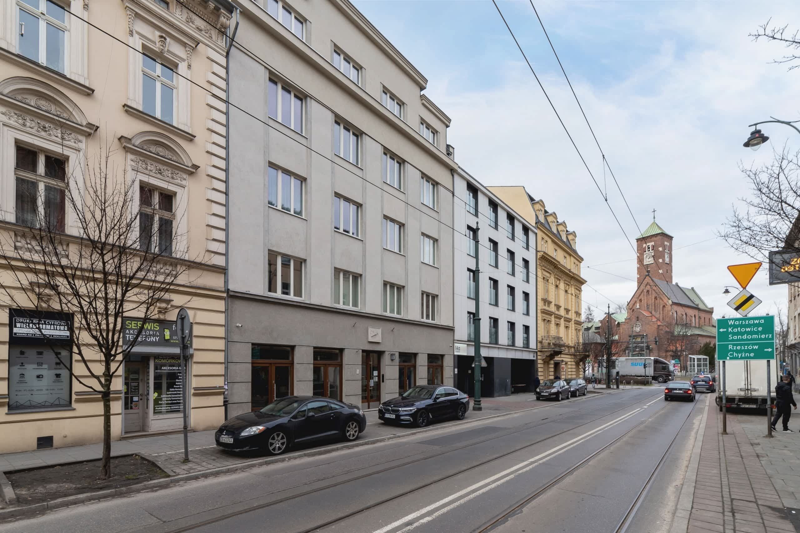 A street view with buildings, cars, and a tram line.