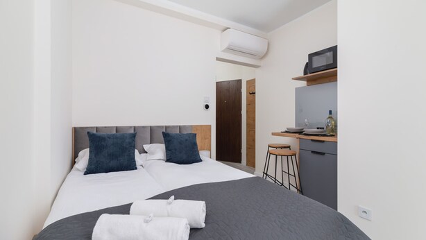 Moderni hotellihuone, jossa on suuri sänky, työpöytä, jossa on mikroaaltouuni, sekä pieni keittokomero.