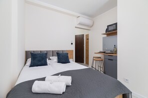 Ett modernt hotellrum med en stor säng, ett skrivbord med mikrovågsugn och ett litet pentry.