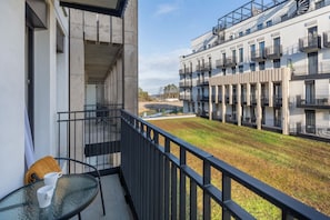 Un balcon avec une table et des chaises, donnant sur une cour intérieure avec un bâtiment en arrière-plan.