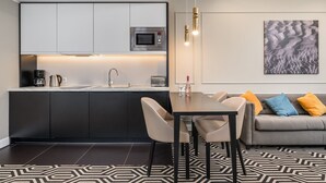 A modern kitchen with a built-in microwave, a coffee machine, and a dining area with a table and chairs. - Sunny Apartment with Parking | Near the Beach | Air Conditioning (Świnoujście)