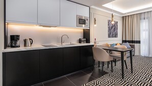 A modern kitchen with a built-in microwave, a coffee maker, and a toaster. There is a dining area with a table and chairs, and a patterned rug on the floor. - Sunny Apartment with Parking | Near the Beach | Air Conditioning (Świnoujście)