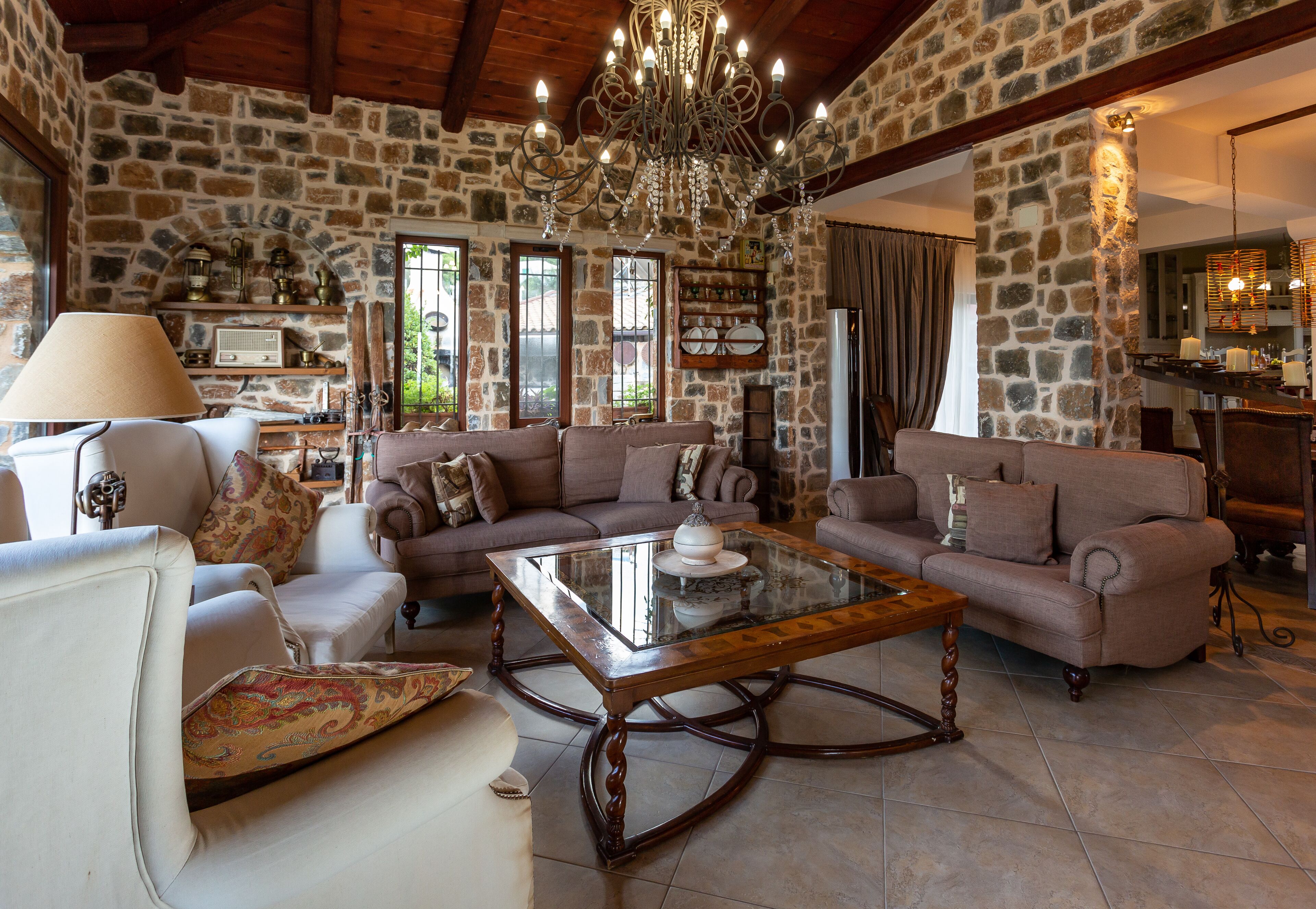 A cozy living room with stone walls, a chandelier, and a fireplace.