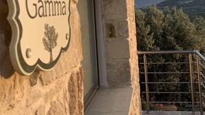 Un bâtiment en pierre avec une enseigne indiquant « OLIVE Gamma » et une vue sur des montagnes en arrière-plan.