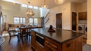 A spacious kitchen with a central island, wooden cabinets, and a built-in microwave. - Woof Lodge at SweetGrass - pet friendly, outdoor fireplace, walk to lake (Blowing Rock)