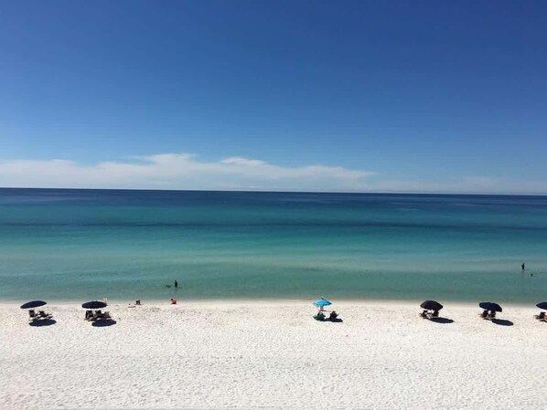 A beach with white sand and clear blue water.