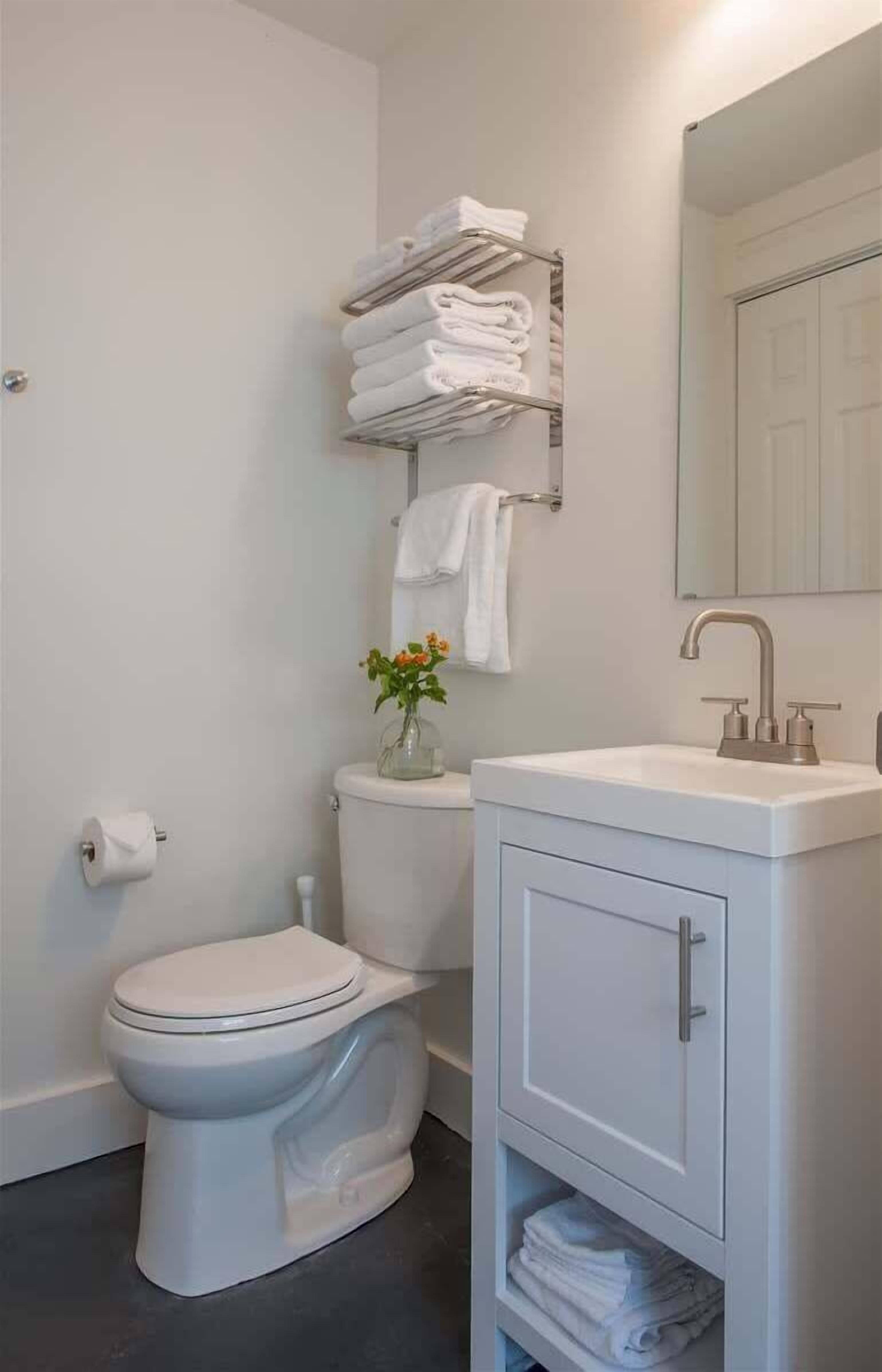 Une salle de bain équipée de toilettes, d’un lavabo, d’un miroir et d’un porte-serviettes.