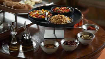 Una mesa de buffet con diversos platos, entre ellos ensaladas, cereales y legumbres, además de salsas y botellas de aceite de oliva.
