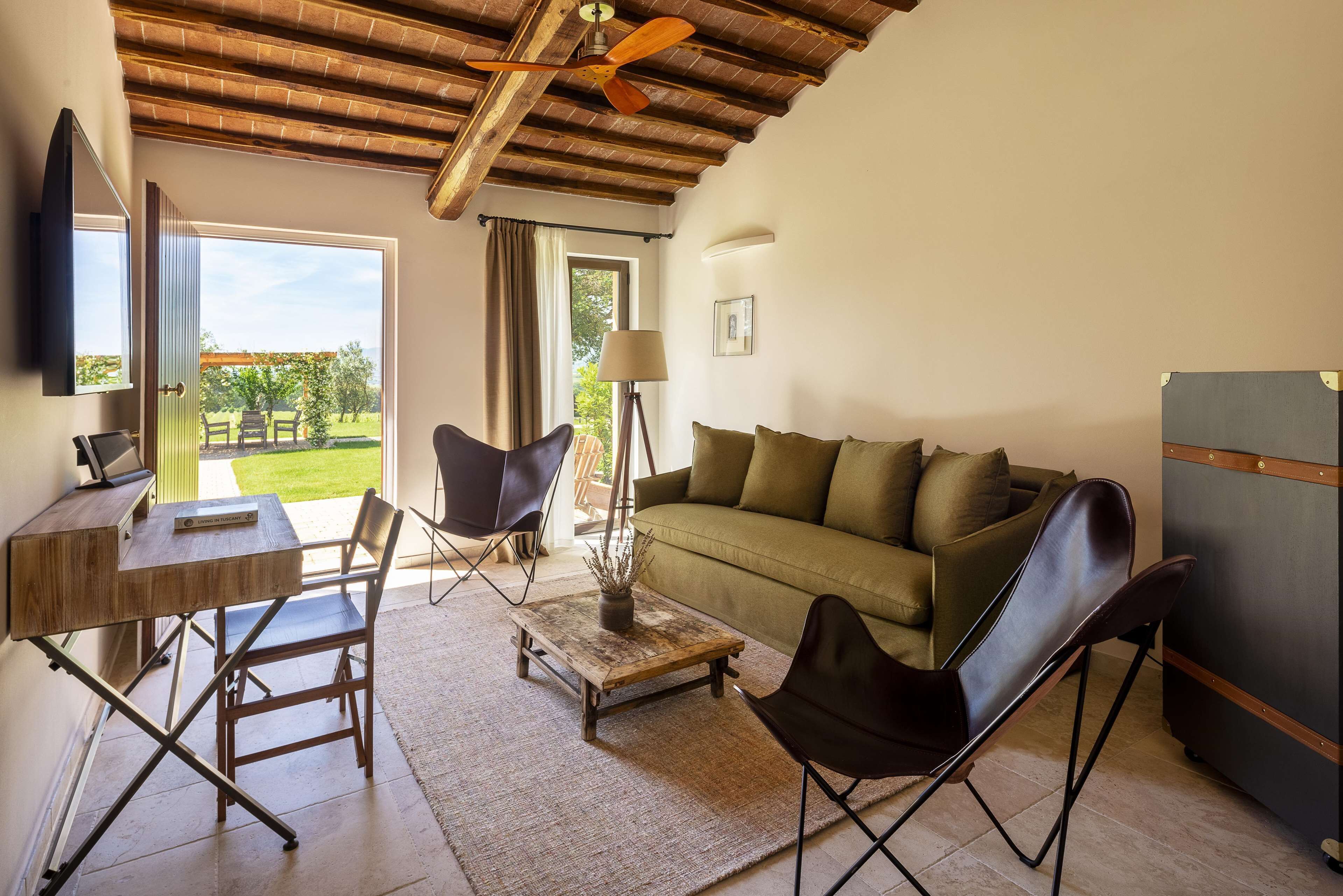 Un salon avec un plafond en bois, un canapé, une table basse, un téléviseur et une vue sur l’extérieur.