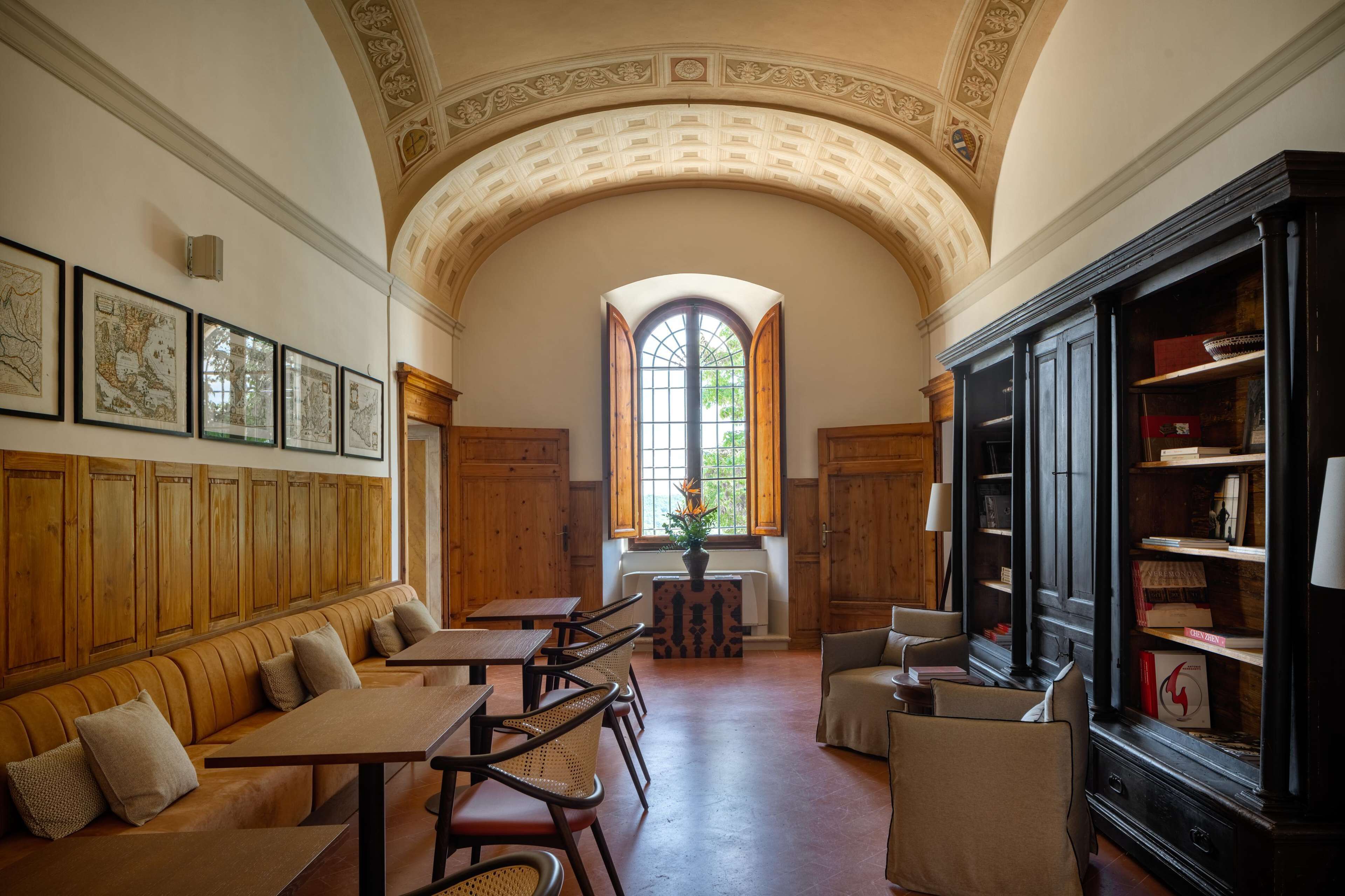 A library with wooden paneling, a large arched ceiling, and a window with open shutters.